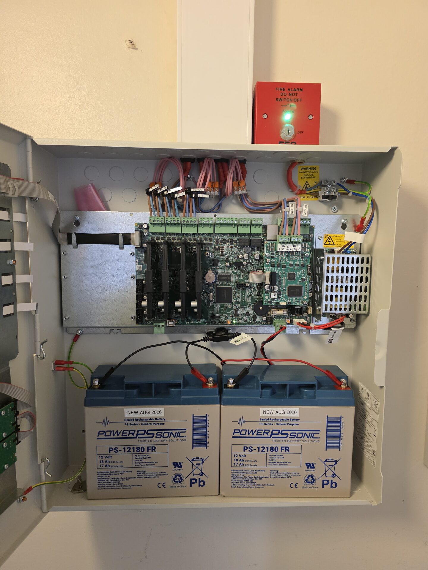 open fire alarm control panel showing PCB and battery backup during commissioning